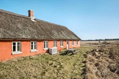 an orange house with a grass roof on a field at BL1249-Pandrup-Rodhus-Klitvej-80 in Pandrup