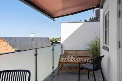 a patio with a wooden table and chairs on a balcony at BL1287-Blokhus-Klitgaardsvej-3-A-1-2 in Blokhus