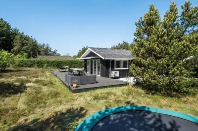 a small black house with a deck in a yard at BL1101-Pandrup-Rodhusparken-56 in Pandrup