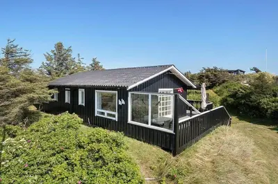 a black tiny house on the side of a hill at BL1100-Blokhus-Klitvejen-44 in Blokhus