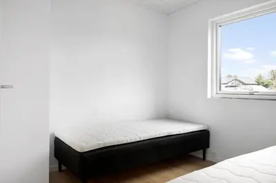 a bed sitting in a room next to a window at BL1108-Saltum-Vesterhavs-Sletten-45 in Saltum