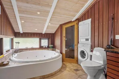 a bathroom with a tub and a toilet and a washing machine at BL1102-Blokhus-Solbakkevej-17 in Blokhus