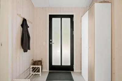 a hallway with a black door and a mirror at BL1765-Blokhus-Plantagevej-2B in Blokhus
