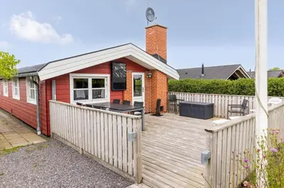 a red house with a wooden deck in front of it at G151-Lemvig-Porsevej-51 in Lemvig