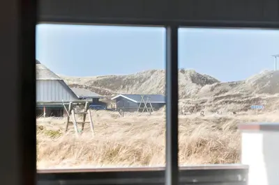a window view of a field with houses and hills at 258-Harboore-Merchantvej-5 in Harboør