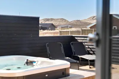 a jacuzzi tub on a patio with two chairs at 258-Harboore-Merchantvej-5 in Harboør