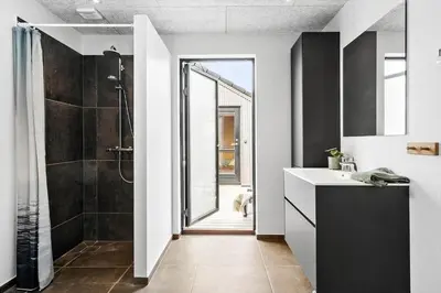 a bathroom with a sink and a shower and a dog at 336-Harboore-Hvilehjemsvej-23 in Harboør