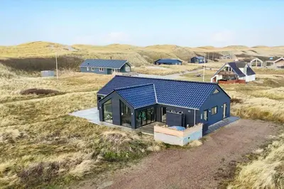 a house with a blue roof in a field at 340-Harboore-Byskovvej-40 in Harboør