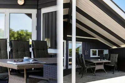 a patio with a table and chairs on a deck at 168-Harboore-Emblavej-1 in Harboør