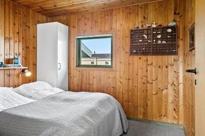 a bedroom with a bed and a window and wooden walls at 157-Harboore-Vejlby-Klit-65 in Harboør