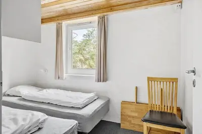 two beds in a room with a window and a chair at 203-Harboore-Viktoriavej-3 in Harboør
