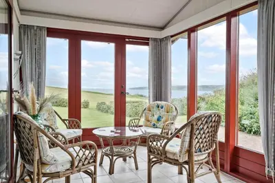 a dining room with a table and chairs and windows at G431-Lemvig-Gyvelvej-31 in Lemvig