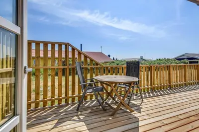 a wooden deck with a table and a chair at 123-Harboore-Vejlby-Klit-83 in Harboør