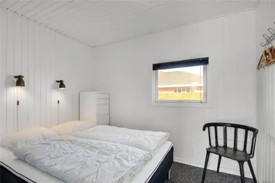 a white bedroom with a bed and a chair at 235-Harboore-Vejlby-Klit-139 in Harboør