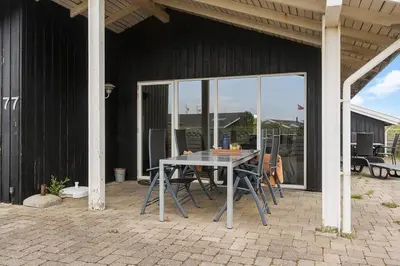 a patio with a table and chairs in front of a building at 153-Harboore-Vejlby-Klit-77 in Harboør