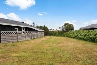 a fence next to a barn with a yard at 153-Harboore-Vejlby-Klit-77 in Harboør