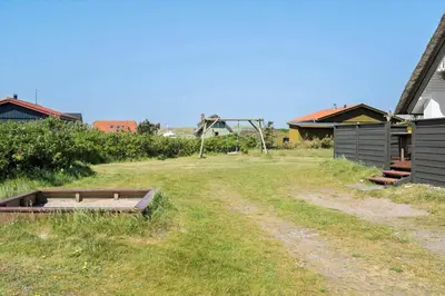 a field with a dirt road next to a house at 300-Harboore-Fourmivej-29 in Harboør