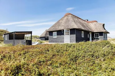 an old house with a thatched roof on a hill at 180-Harboore-Doblervej-89 in Harboør