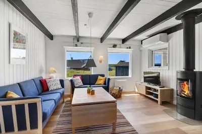 a living room with a blue couch and a fireplace at 301-Harboore-Themisvej-11 in Harboør