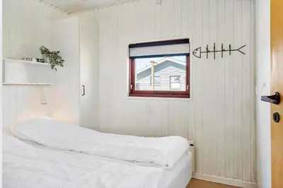 a white bedroom with a bed and a window at 154-Harboore-Vejlby-Klit-103 in Harboør