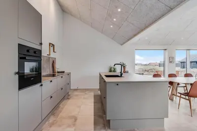 a kitchen with white cabinets and a table with chairs at 350-Harboore-Alkajavej-13-A in Harboør