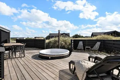 a deck with a table and chairs and a fire pit at 332-Harboore-Hvilehjemsvej-20 in Harboør