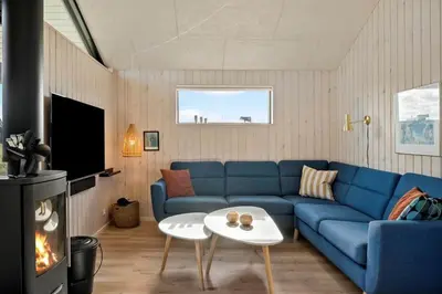 a living room with a blue couch and a fireplace at 332-Harboore-Hvilehjemsvej-20 in Harboør