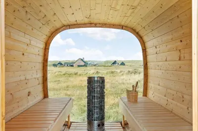 an arched window in a wooden cabin with a view of a field at 360-Harboore-Alkajavej-11 in Harboør