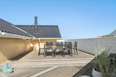 a deck with chairs and a table on a house at 127-Harboore-Vejlby-Klit-237 in Harboør