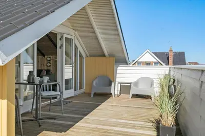 a porch with chairs and a table on a house at 127-Harboore-Vejlby-Klit-237 in Harboør