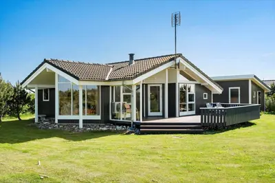a small house with a large porch on a lawn at 104-Harboore-Neerlandiavej-29 in Harboør
