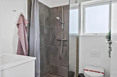a bathroom with a shower with a toilet and a window at 252-Harboore-Amazonevej-6 in Harboør