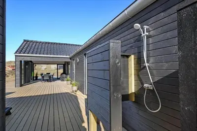 a wooden deck with a shower on the side of a house at 252-Harboore-Amazonevej-6 in Harboør