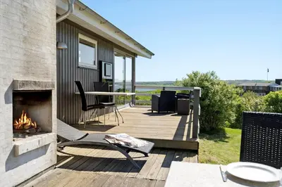 a deck with a fireplace and a table and chairs at G319-Lemvig-Violvej-19 in Lemvig