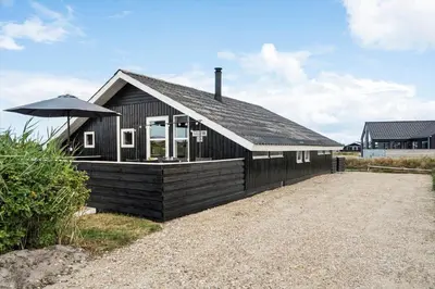 a black house with an umbrella in front of it at 117-Harboore-Neerlandiavej-224 in Harboør