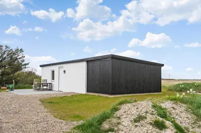 a black and white shed with a table in a field at 370-Harboore-Strandvejen-53 in Harboør