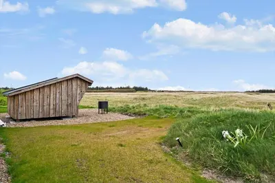 a small wooden shed in a field with a grass field at 370-Harboore-Strandvejen-53 in Harboør