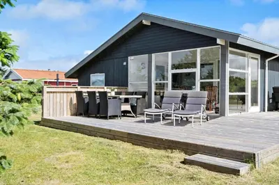a house with a wooden deck with chairs and a table at 204-Harboore-Vejlby-Klit-33 in Harboør