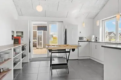 a kitchen with a table and a chair in it at 148-Harboore-Lucievej-6-a in Harboør
