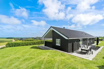 a black cottage with a table and chairs on a lawn at G509-Lemvig-Myntevej-9 in Lemvig