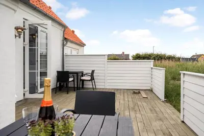 a patio with a table and chairs and a white fence at 324-Harboore-Skalvej-4-b in Harboør