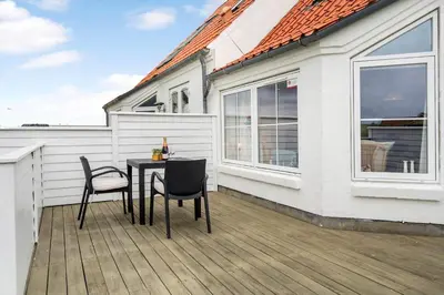 a table and chairs on a deck next to a house at 324-Harboore-Skalvej-4-b in Harboør