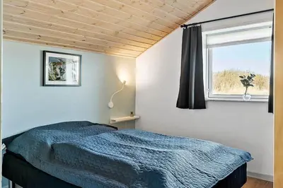 a bedroom with a blue bed and a window at 149-Harboore-Vejlby-Klit-175 in Harboør