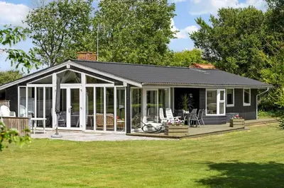 a house with a conservatory with chairs on a lawn at 605-Lemvig-Gjelleroddevej-65 in Lemvig