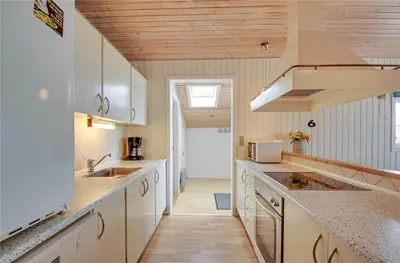 a kitchen with white cabinets and a wooden ceiling at 145-Harboore-Neerlandiavej-98 in Harboør