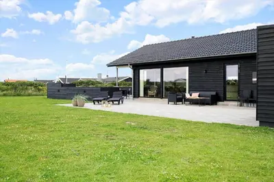 a black house with a patio and grass at 237-Harboore-Neerlandiavej-17 in Harboør