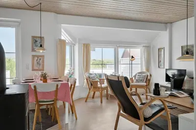 a dining room and living room with a table and chairs at 325-Harboore-Skalvej-4-c in Harboør