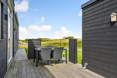a patio with a table and chairs on a deck at G408-Lemvig-Violvej-8 in Lemvig
