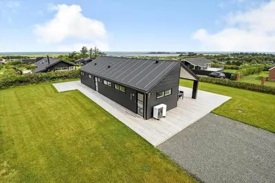 a house with a black roof on a green field at G307-Lemvig-Bynkevej-7 in Lemvig