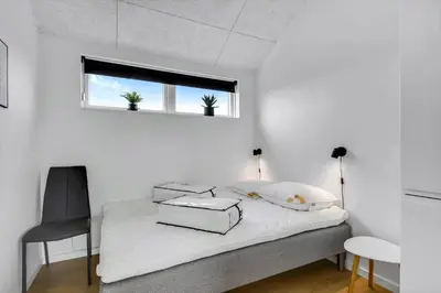 a bedroom with a bed with a chair and a window at G307-Lemvig-Bynkevej-7 in Lemvig